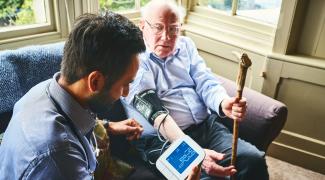 Older man with CNA, blood pressure monitoring
