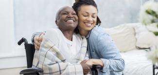 Woman in wheelchair with CNA, hug